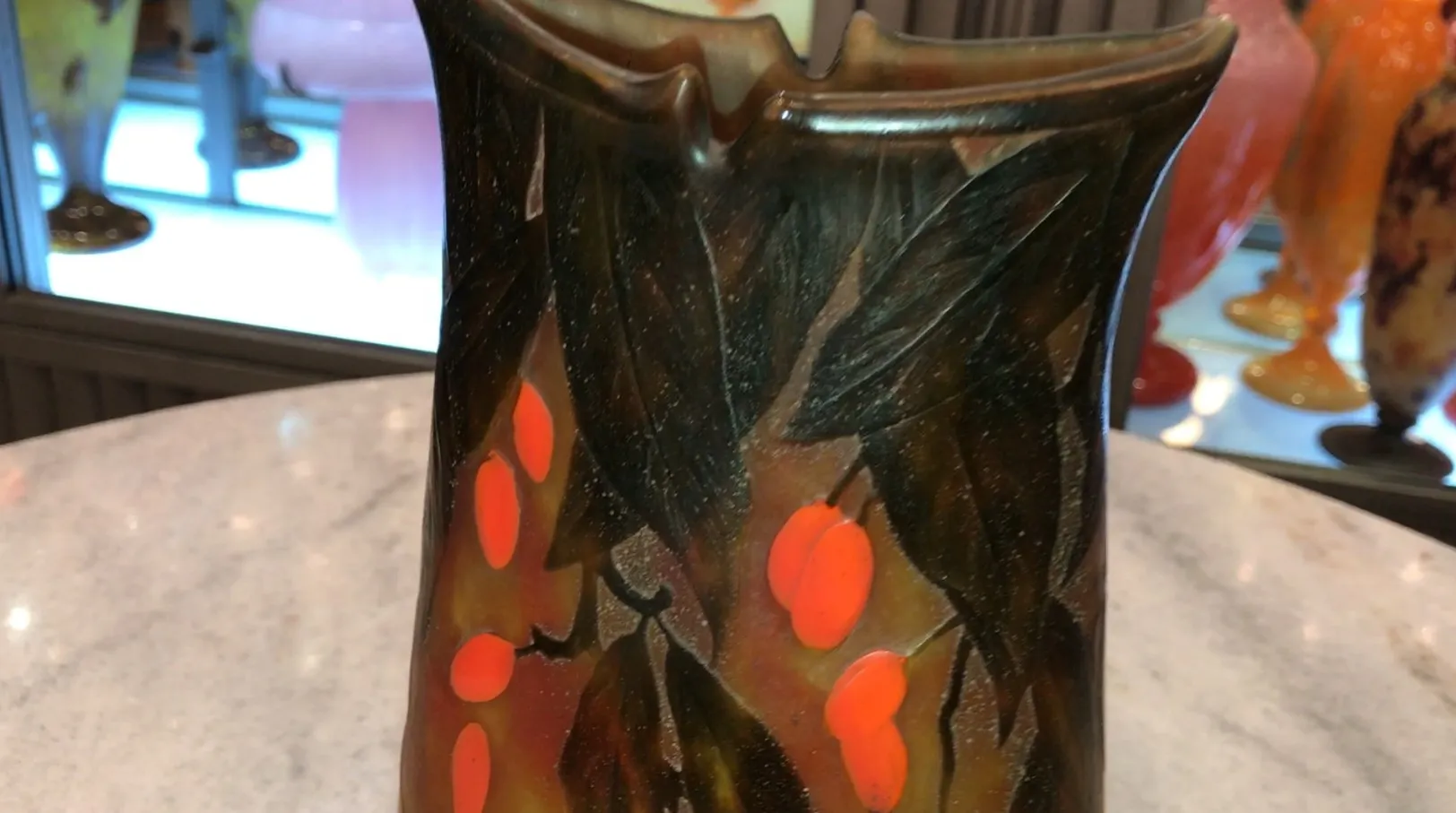 Antike Vase mit dunklen Blättern und roten Früchten, signiert.