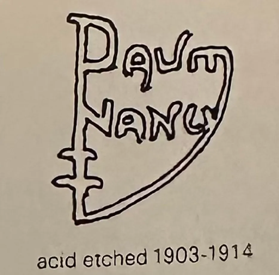 Inscripción de Daum Nancy con técnica de grabado ácido sobre fondo claro.