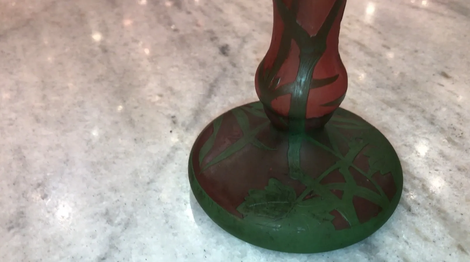 Verre signé Daum Nancy avec motif floral en rouge et vert, sur fond de marbre.