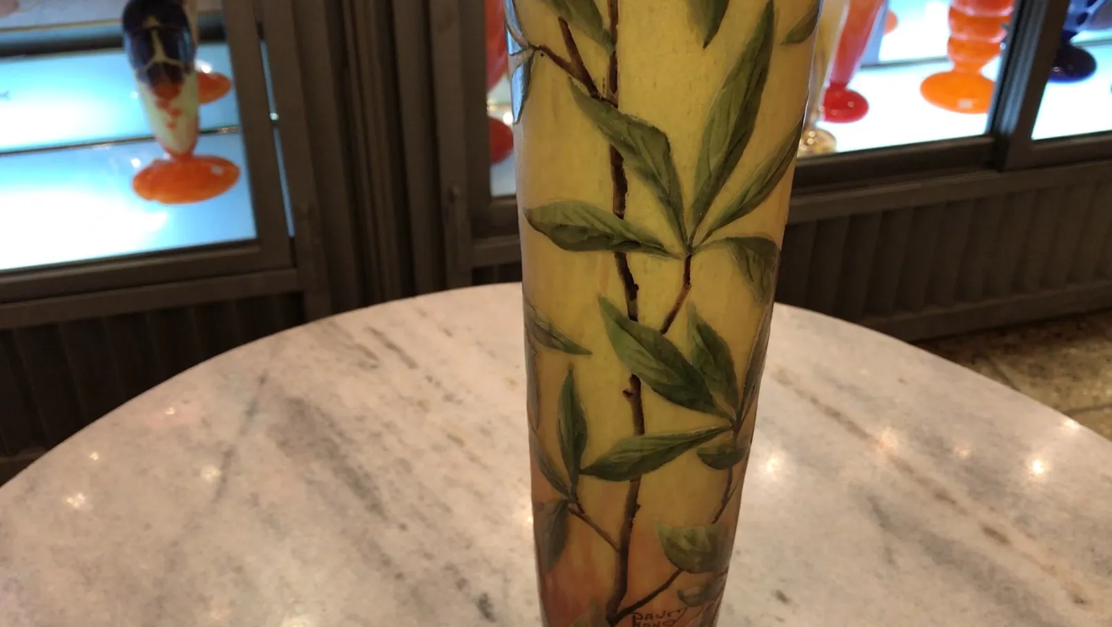 Verre signé avec des feuilles vertes sur fond jaune dans un cadre ancien.