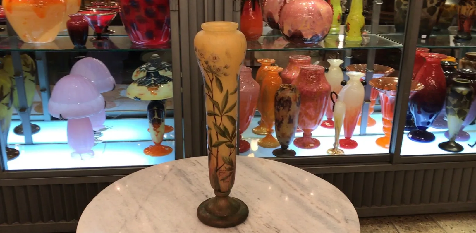 Vidro assinado Daum Nancy com design floral e cores suaves em um ambiente de antiguidades.