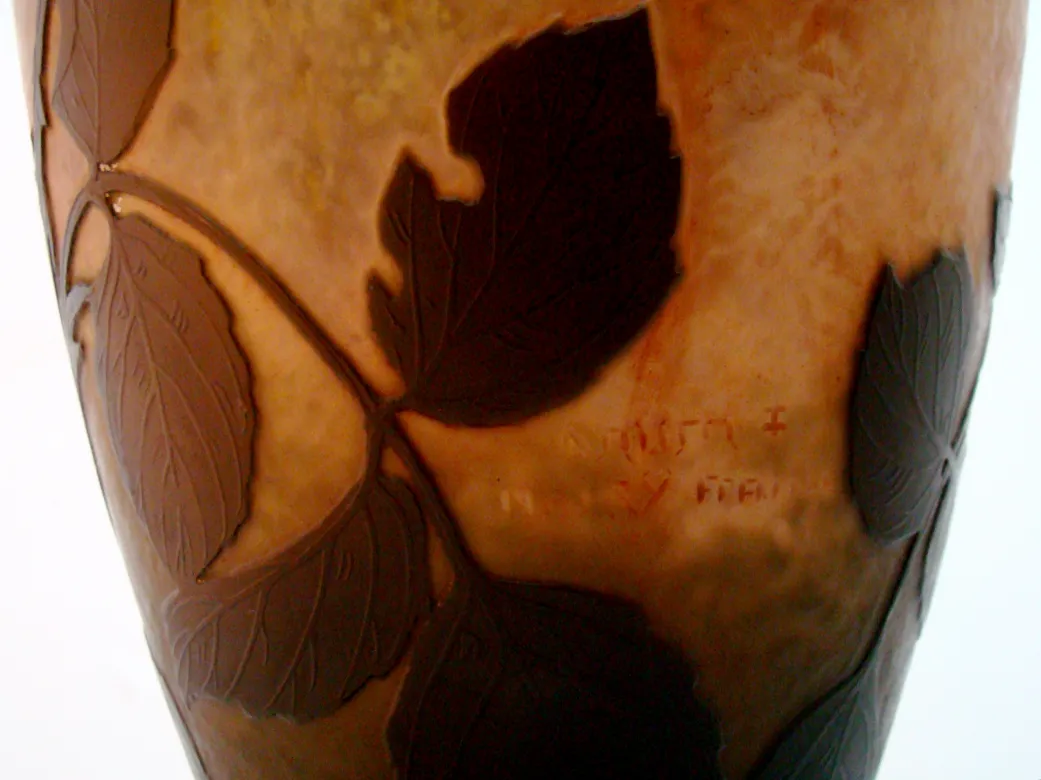 Verre signé Daum Nancy avec motif de feuilles dans des tons chauds.