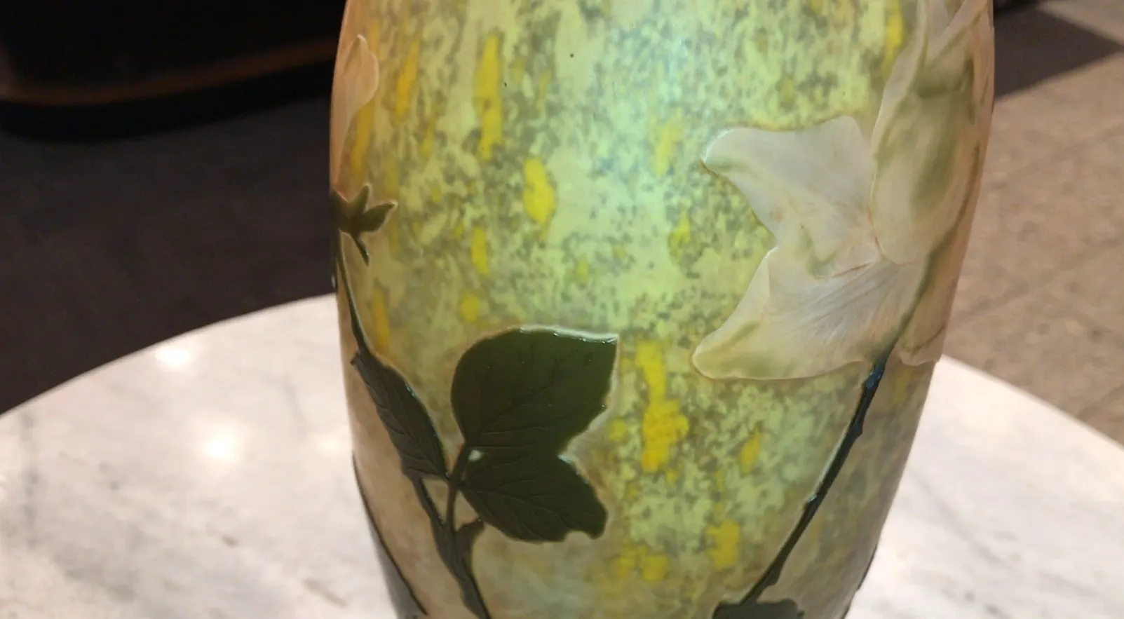 Verre antique signé Daum Nancy avec des motifs floraux dans un cadre chaleureux.