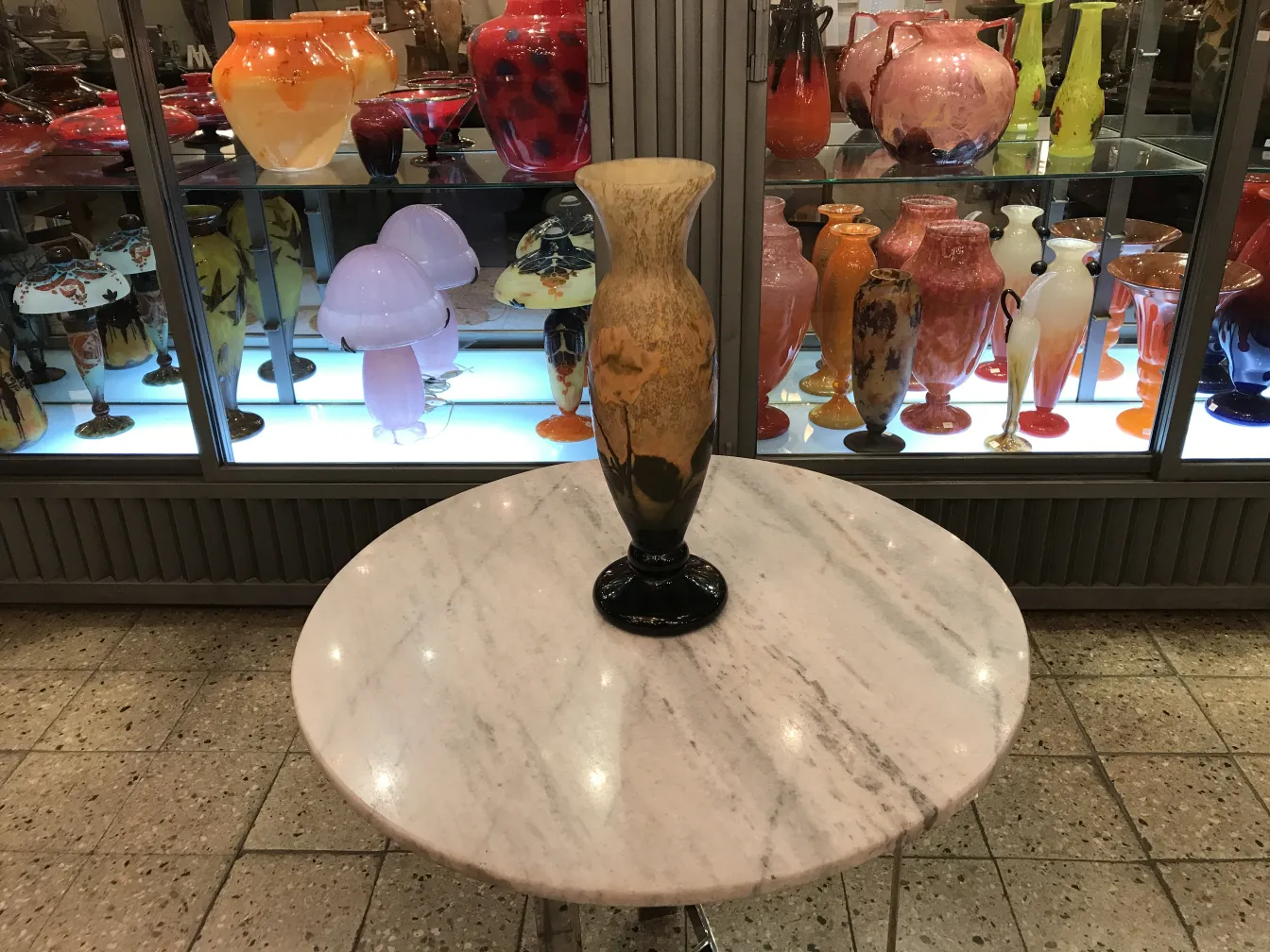 Antiker Vase mit Daum Nancy Unterschrift, umgeben von anderen bunten Glasantiquitäten.