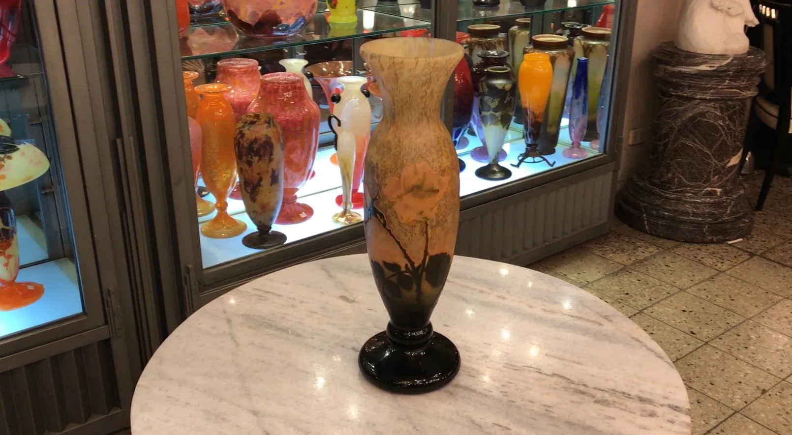 Vaso antico in vetro firmato Daum Nancy esposto tra altre antichità colorate.