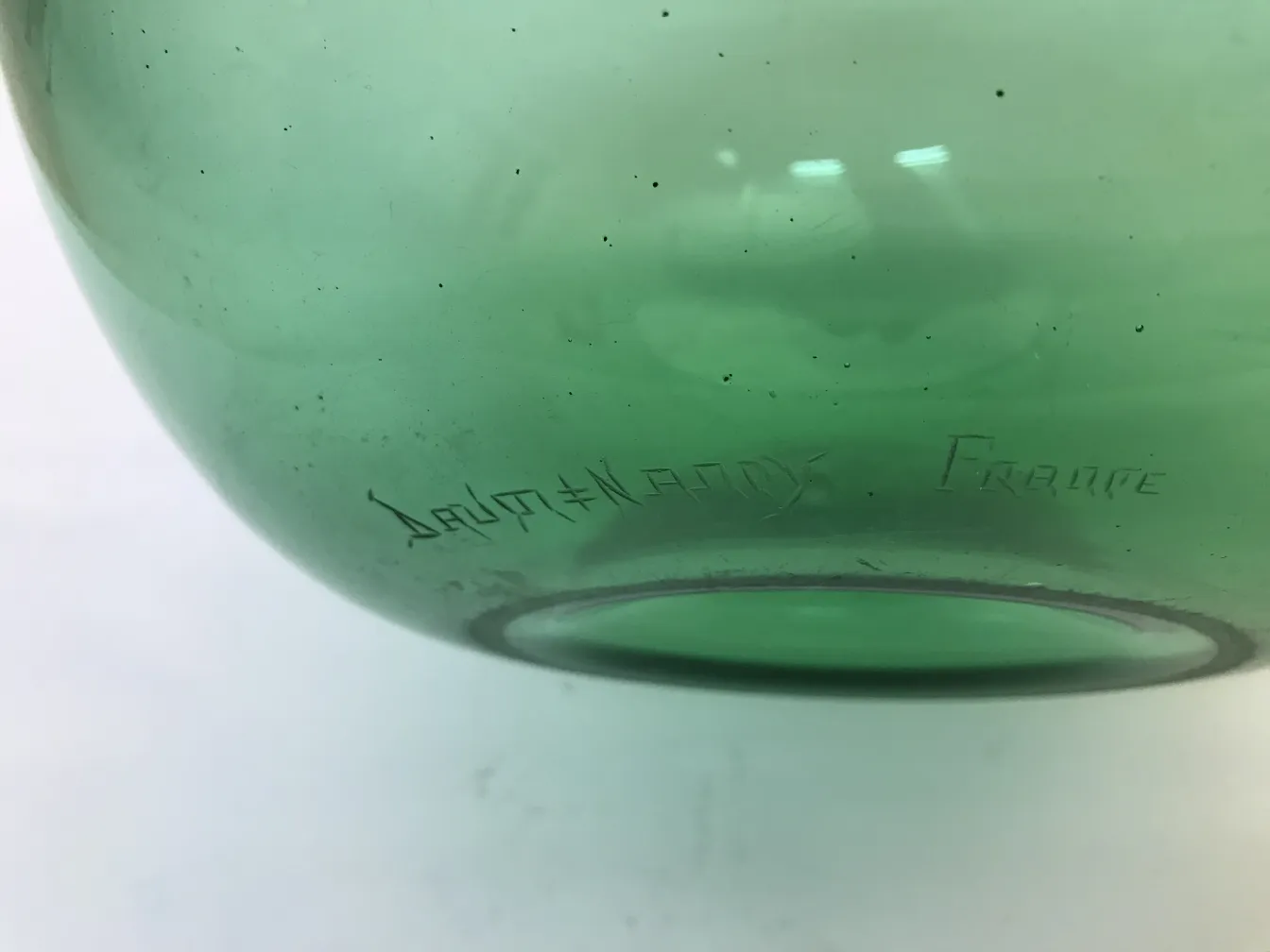 Verre vert avec signature 'Daum Nancy', style ancien, fond blanc.