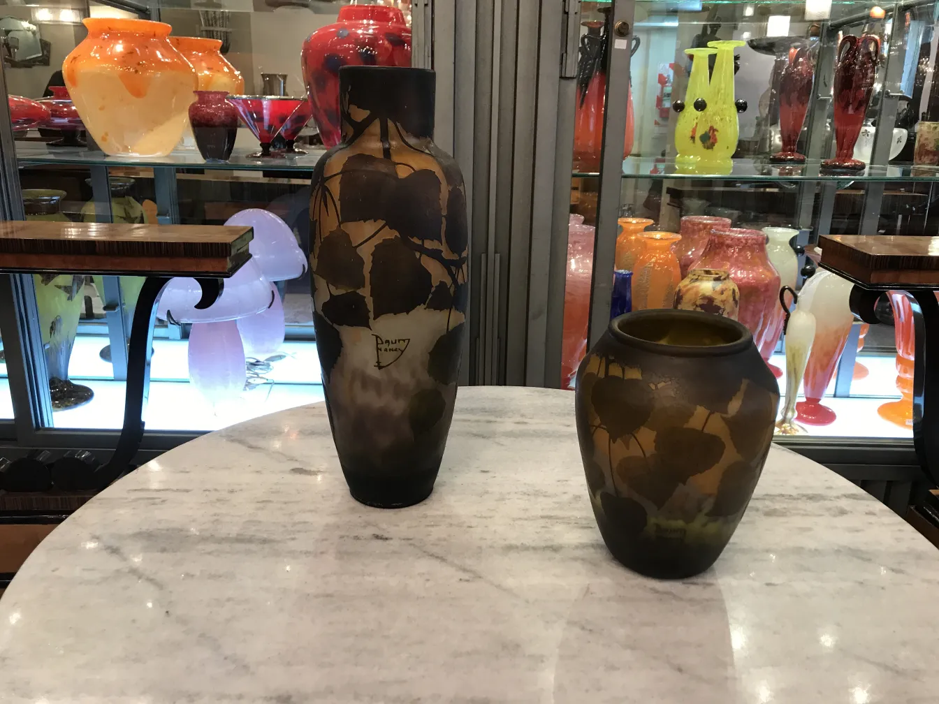 Dos jarrones antiguos firmados en la mesa con variedad de colores de fondo