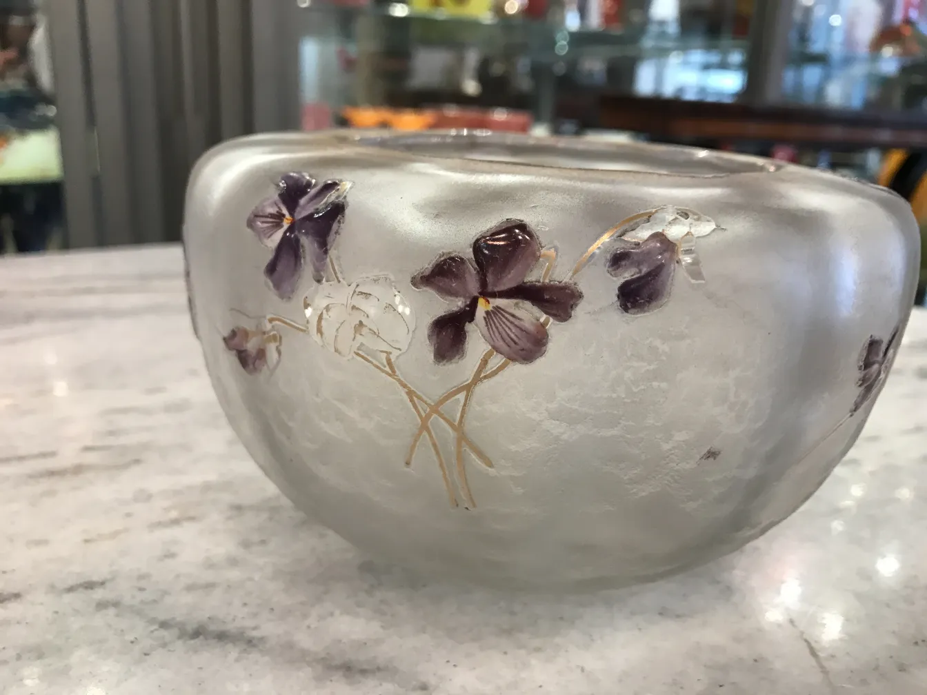 Vidrio antiguo con flores talladas, firmado por Daum Nancy, en un entorno clásico.