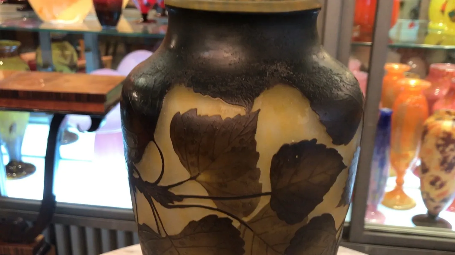 jarre ancienne en verre avec motif de feuilles, signature visible daum nancy, fond coloré