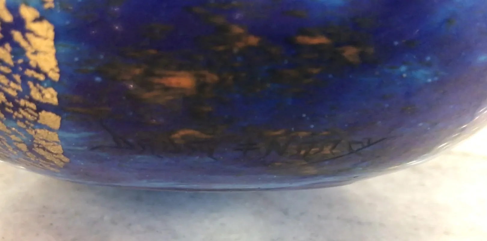 Blue signed glass Daum Nancy with golden details on a light background.