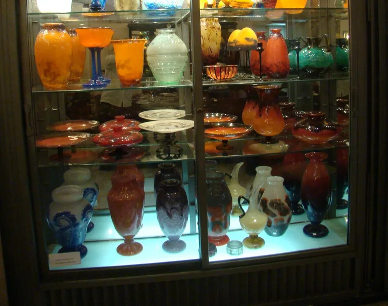 signiertes glas daum nancy in einer vitrine mit anderen bunten glasobjekten
