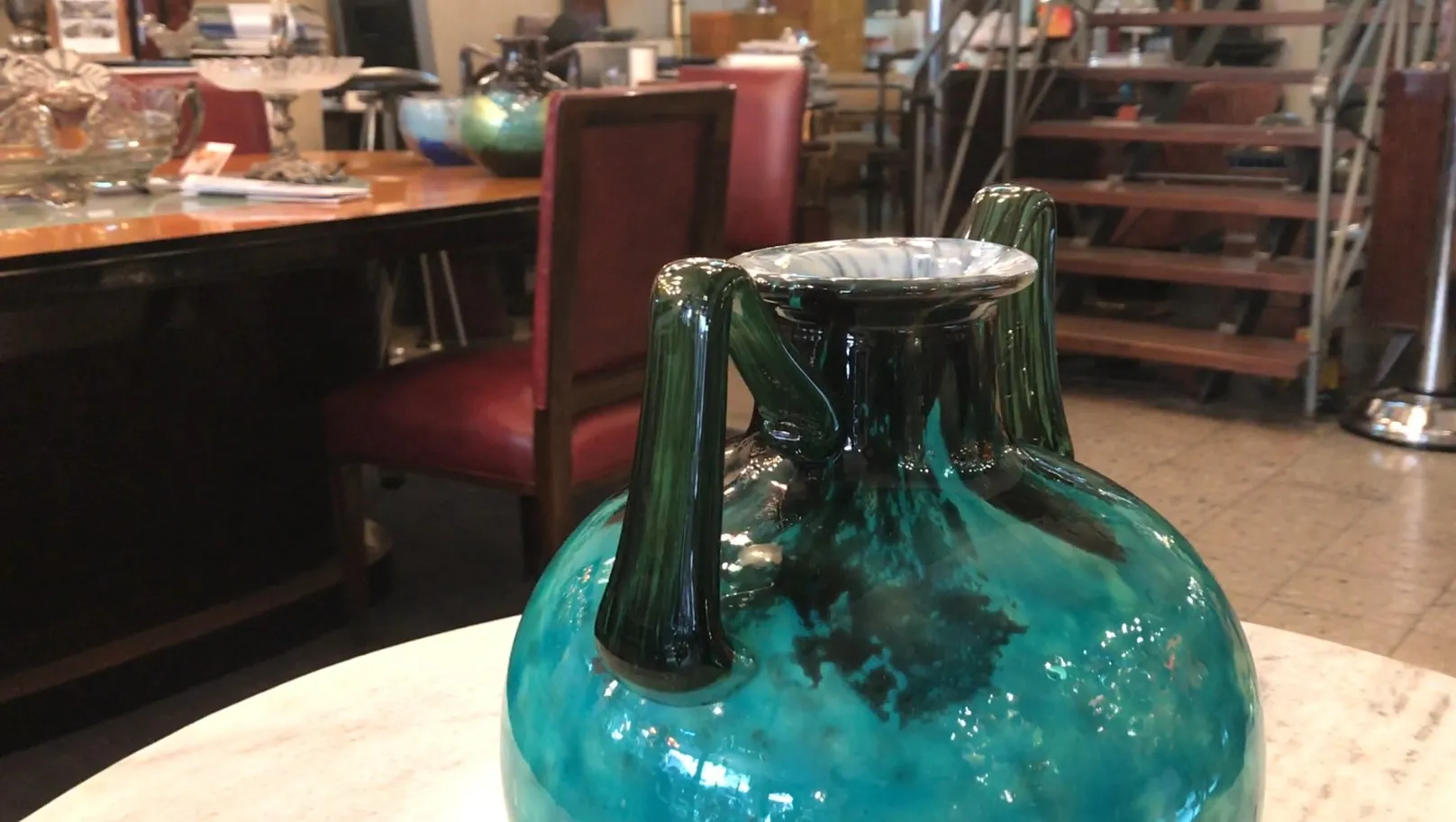 Verre ancien signé daum nancy, forme ronde avec poignées vertes, posé sur une table en marbre.