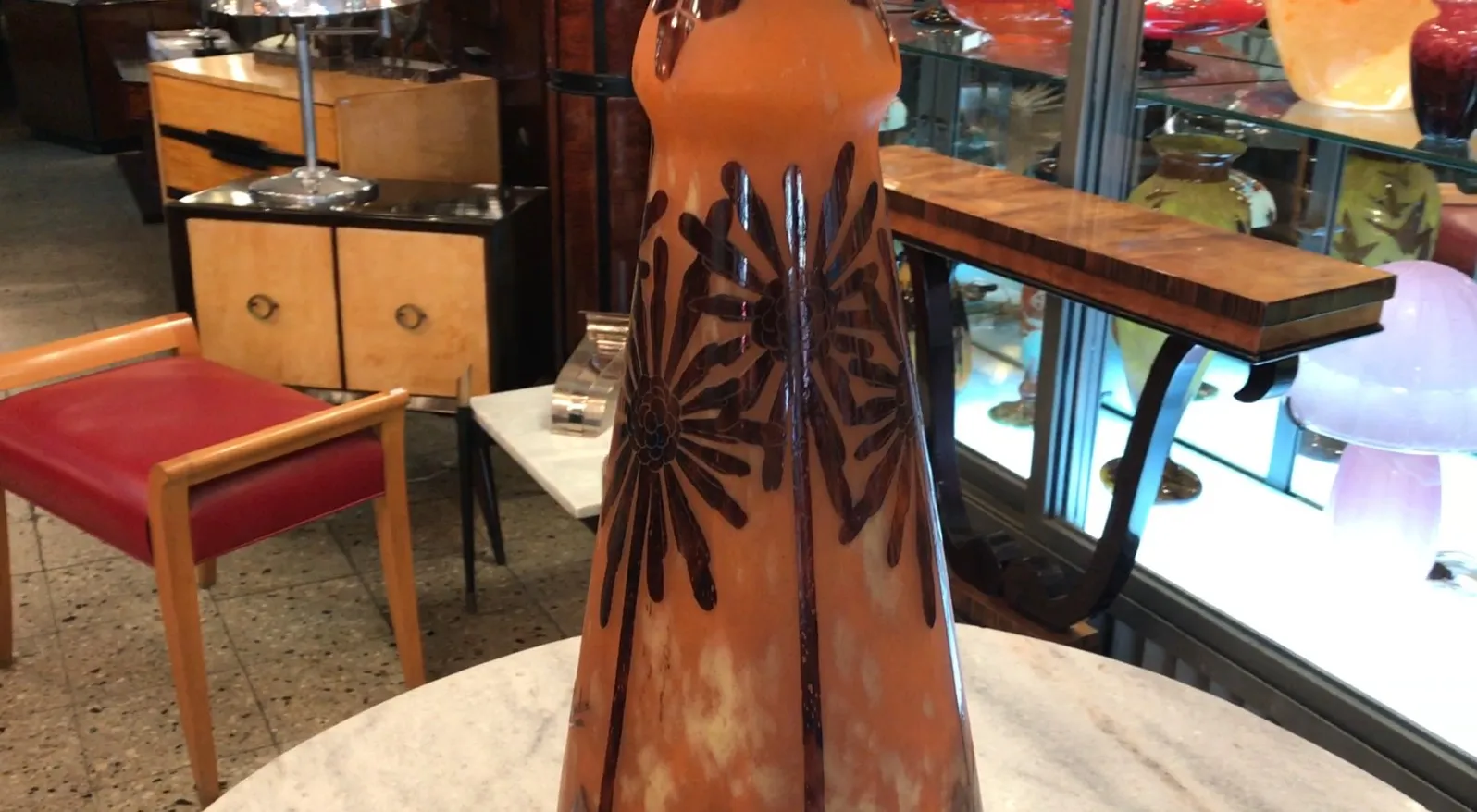 Vidro antigo assinado Charder, decorado com flores escuras, em um ambiente de antiguidades