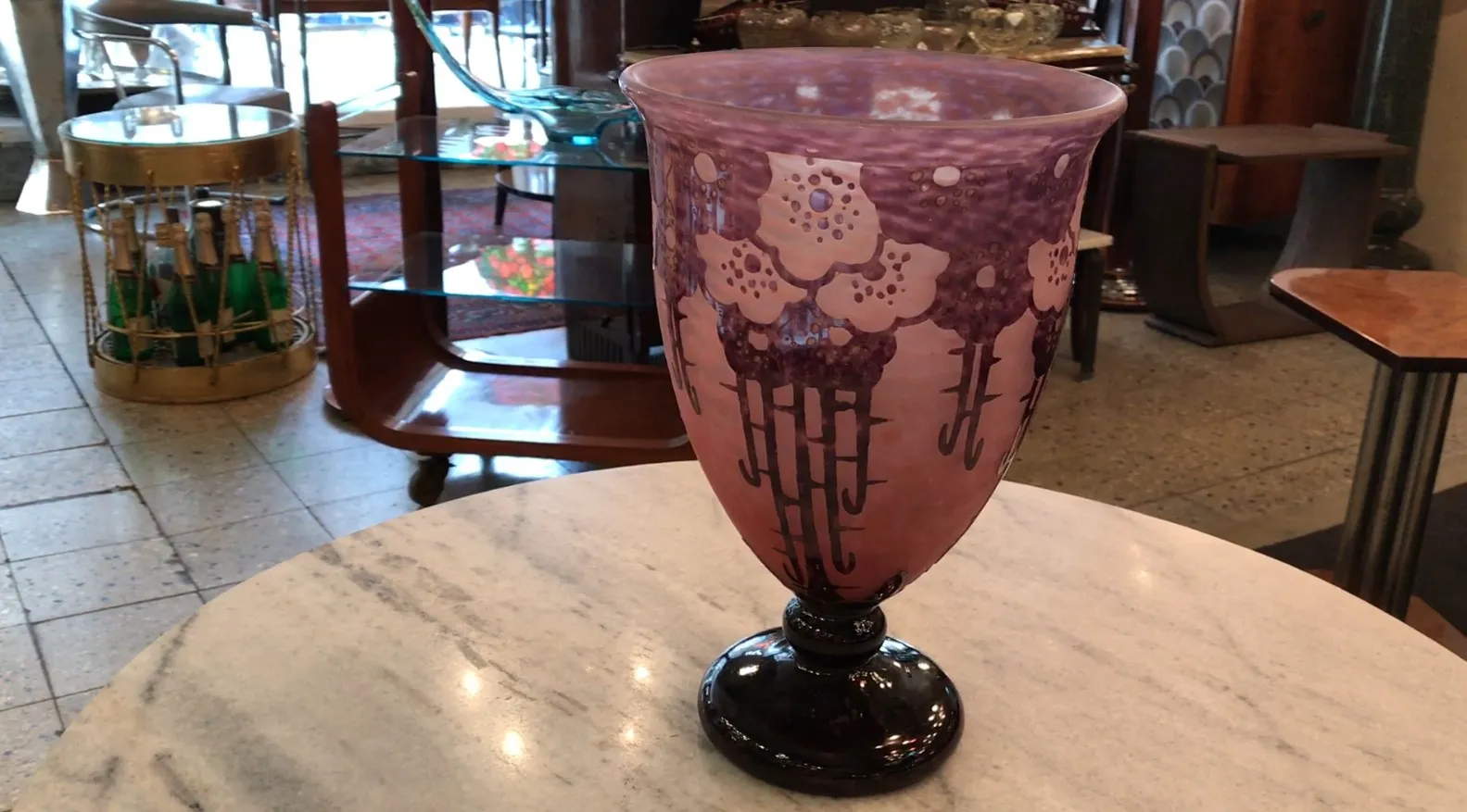 Verre signé Charder avec décoration florale en tons de violet placé sur une table en marbre.