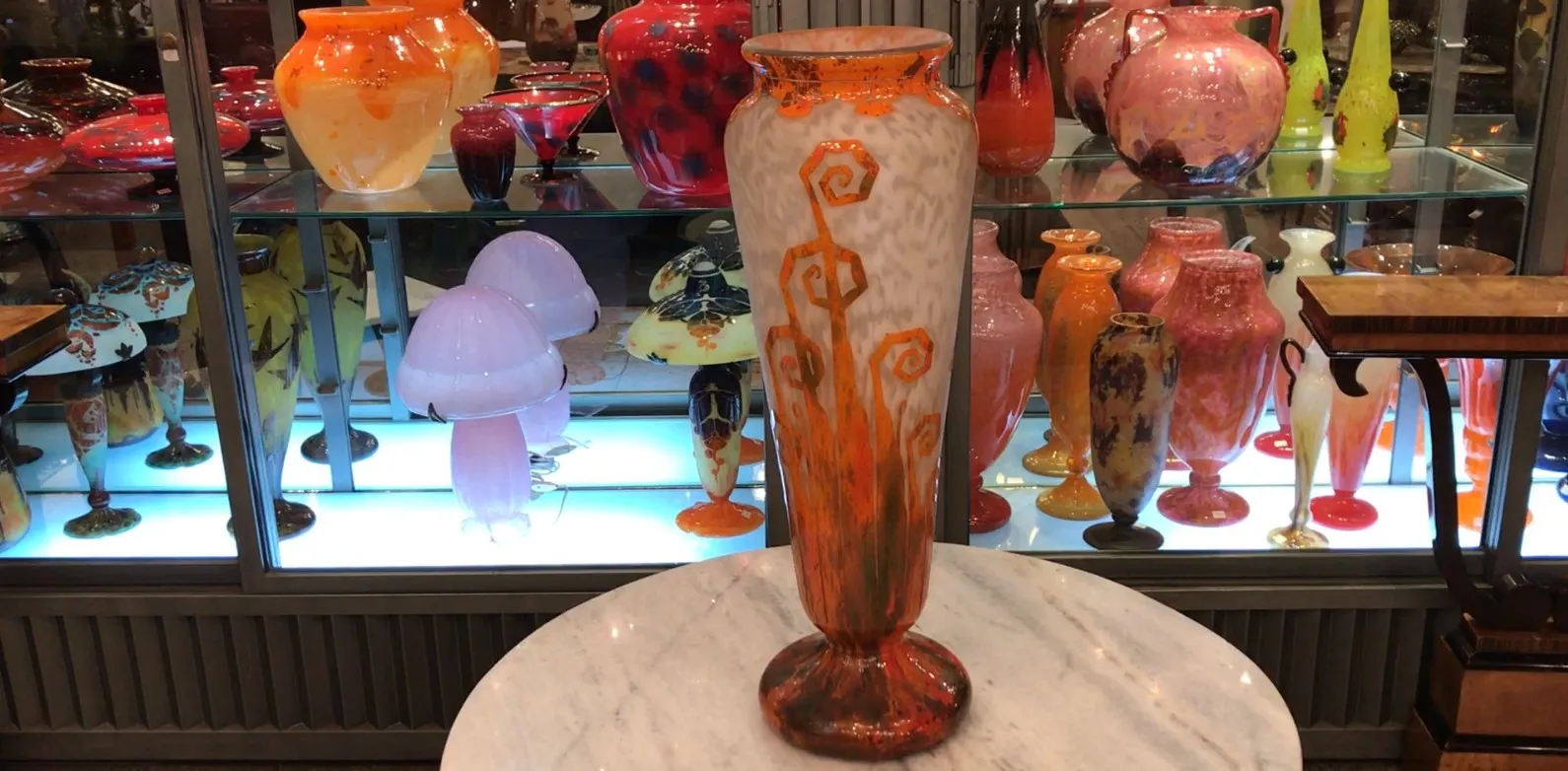 Signiertes Glas von Charder mit orange-weißer Dekoration in beleuchtetem Regal