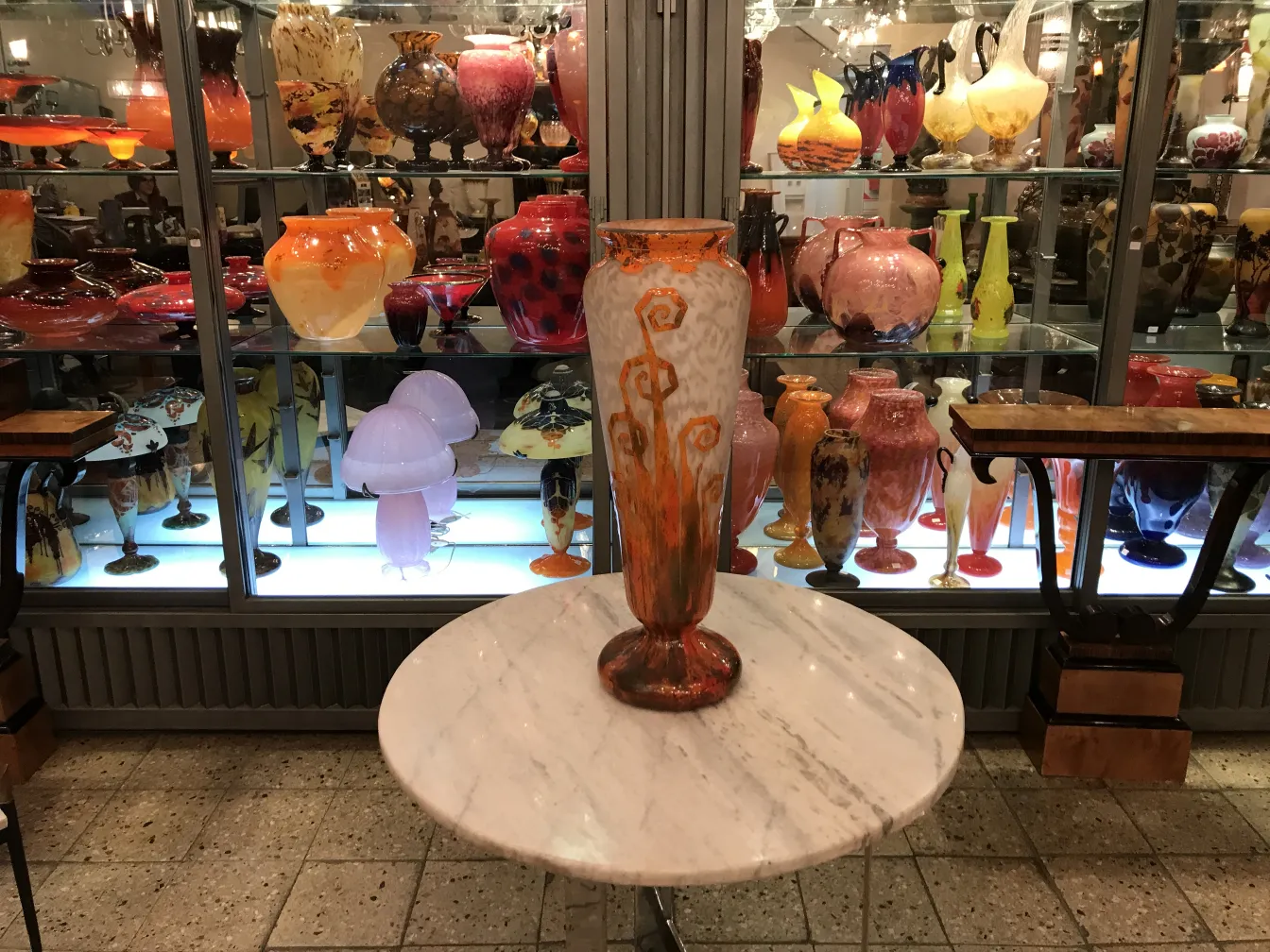 Antique glass vase signed by Charder, beautifully designed and colorful, amidst other collectible items.