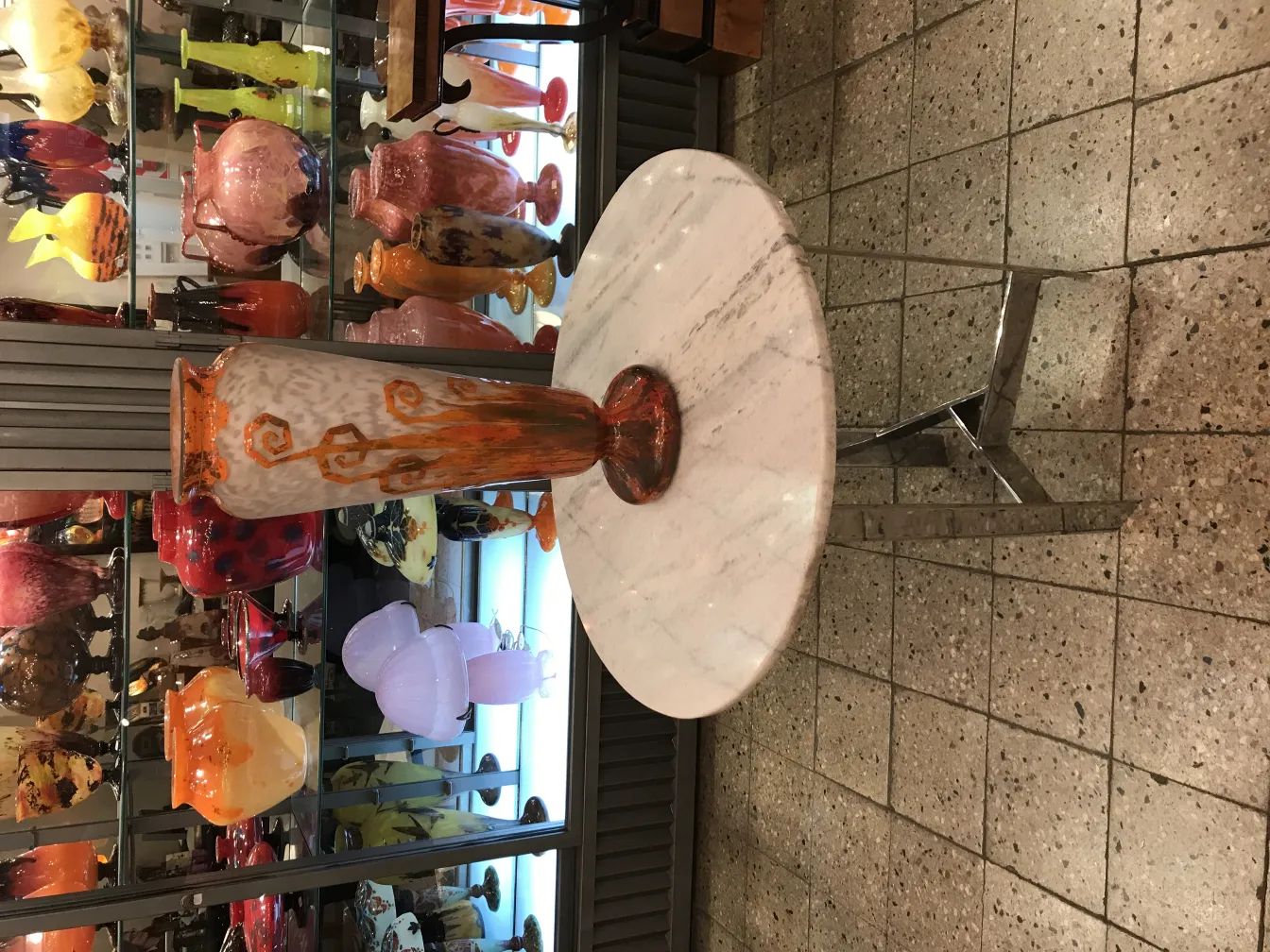 Vase en verre signé avec un design coloré dans une vitrine éclairée.