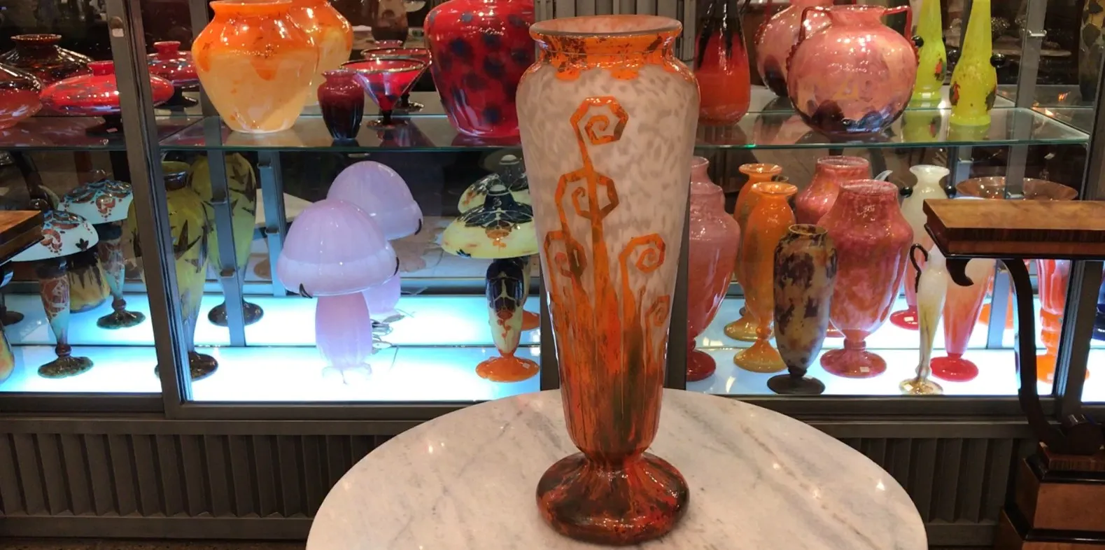 Antique vase with orange and white design, signed by Charder, alongside other glass items.