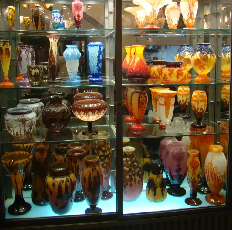 Sammlung von Antiquitäten mit signiertem Glas von Charder in einem Schaukästchen.