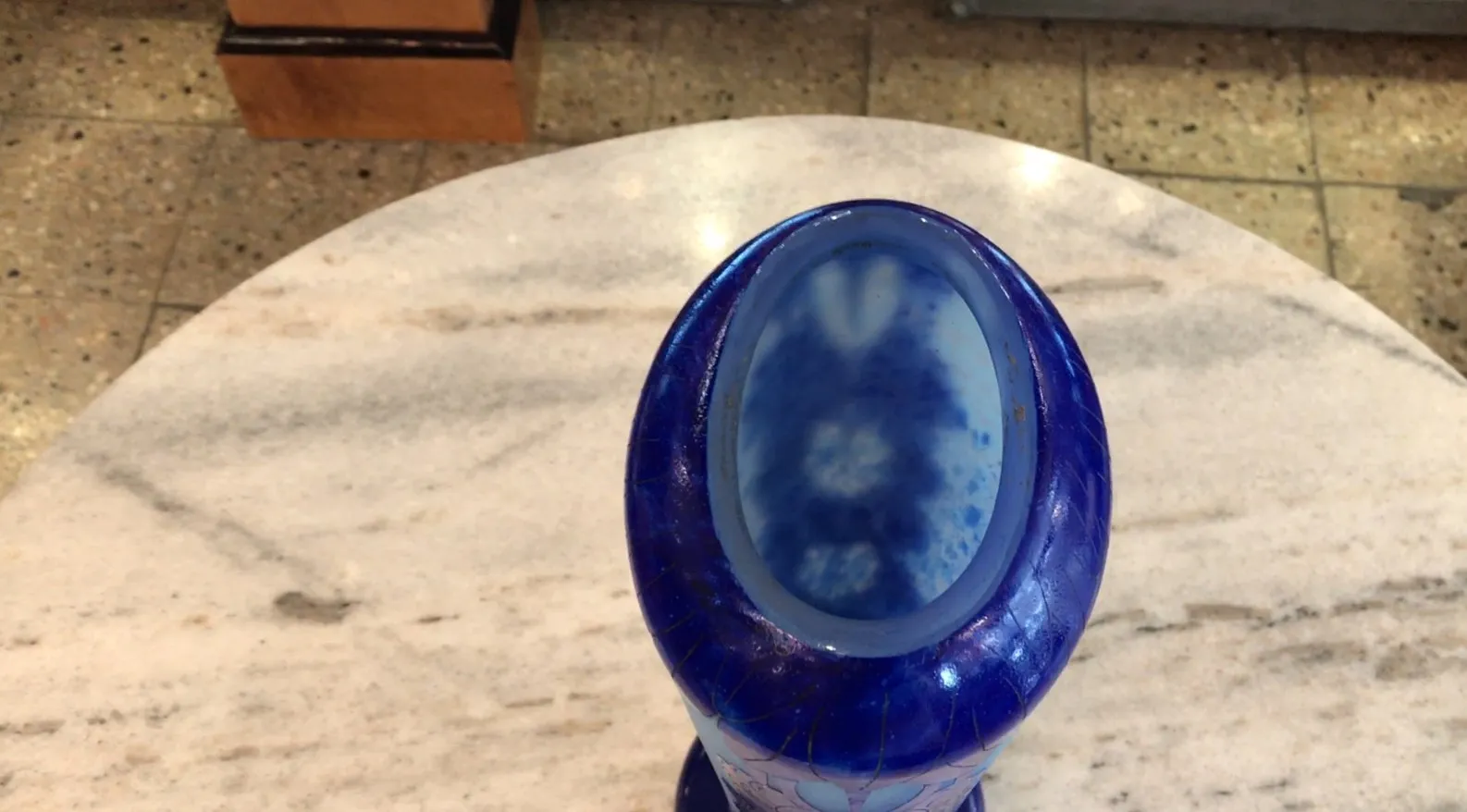 Vidro antigo assinado Charder em forma oval azul, decorativo sobre mesa branca.