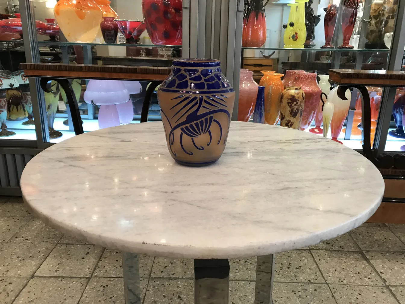 Jarra de vidrio con diseño azul y fondo beige, antigüedad.