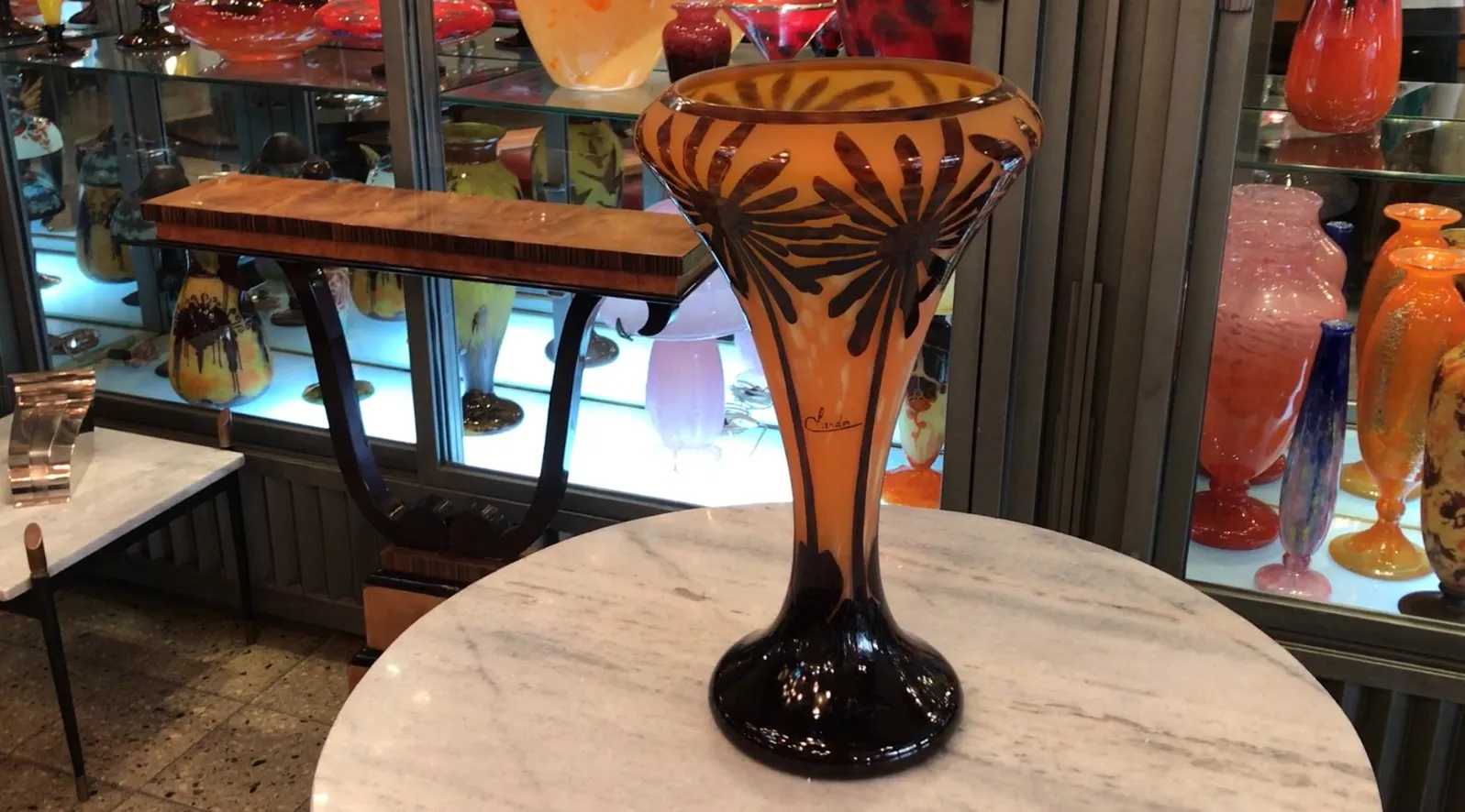 Antique glass vase signed by Charder with black floral design on amber background.