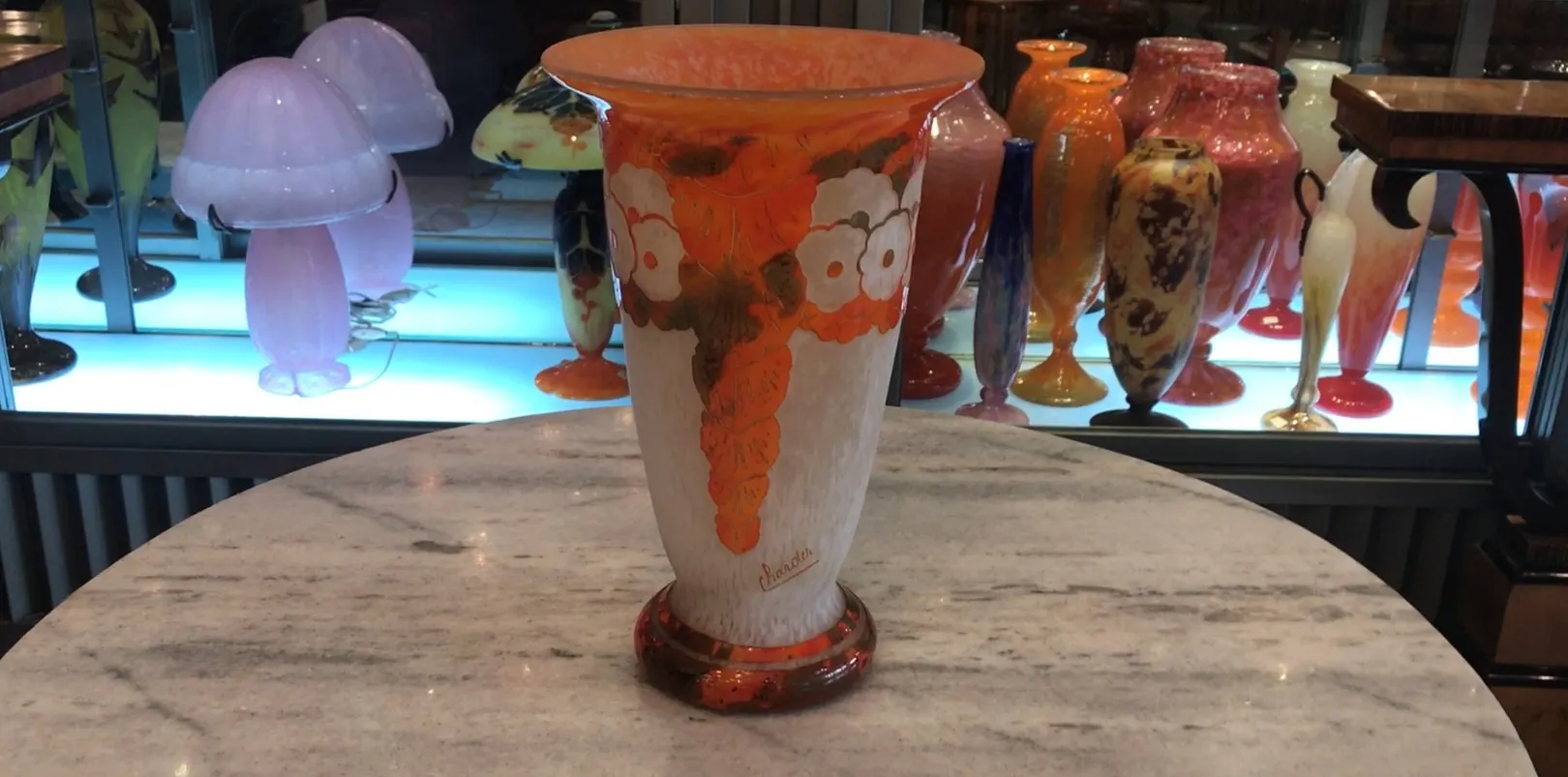 Vase en verre signé Charder avec motif en couleurs chaudes. Fond d'antiquités.