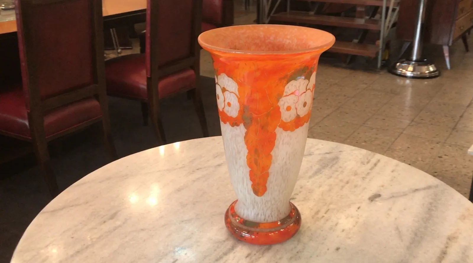 Vaso de vidro assinado Charder com designs florais em tons de laranja e branco. Ambiente acolhedor