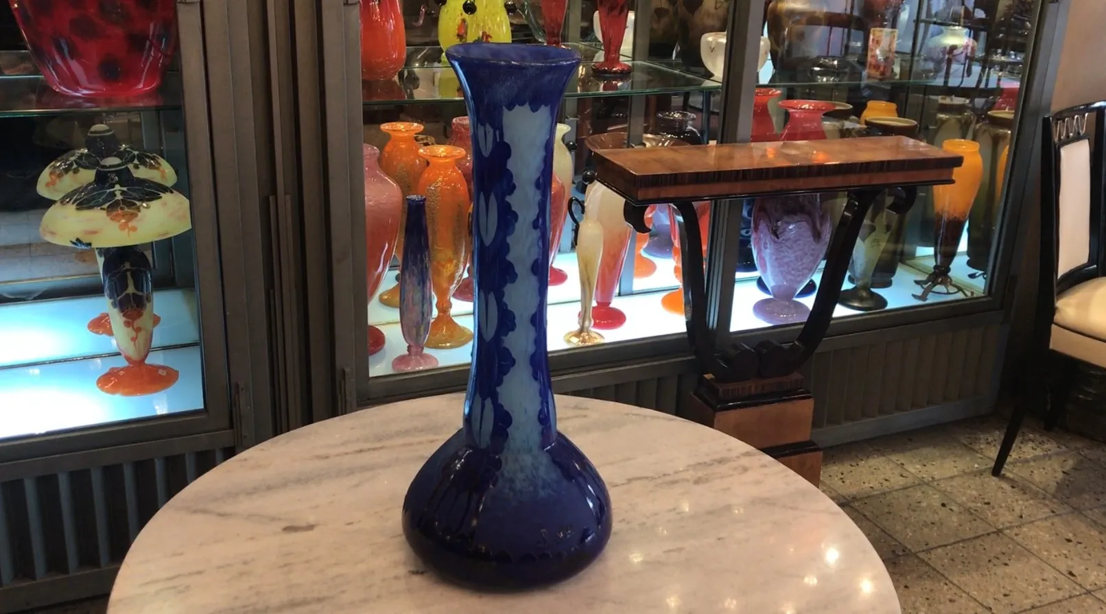 Vidrio azul firmado Charder en frente de otros objetos coloridos