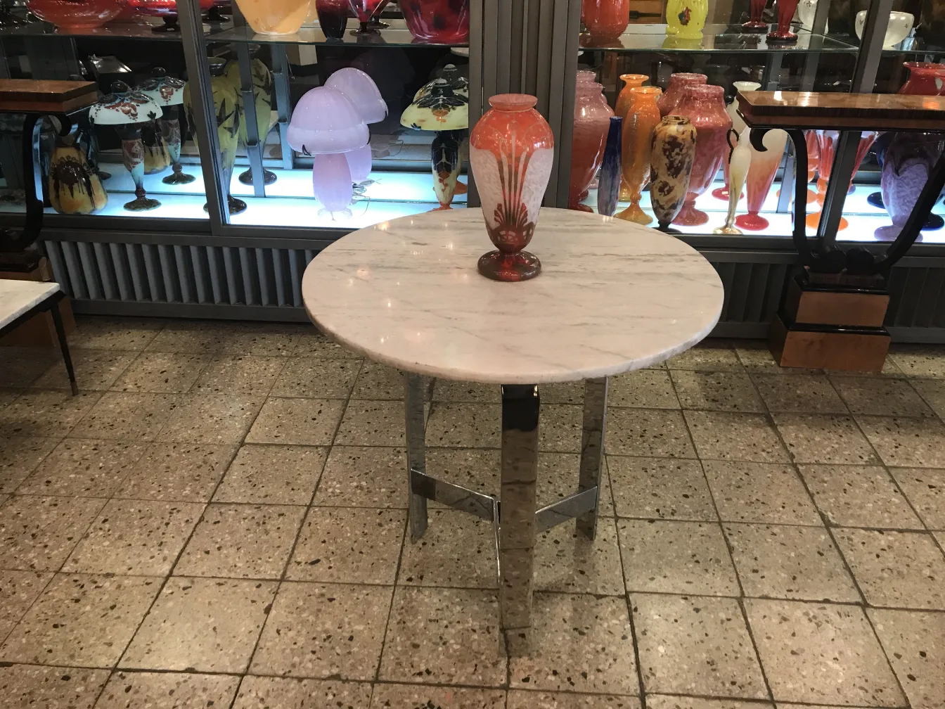 Antiguo vidrio firmado Charder sobre mesa, con jarrones de colores de fondo.