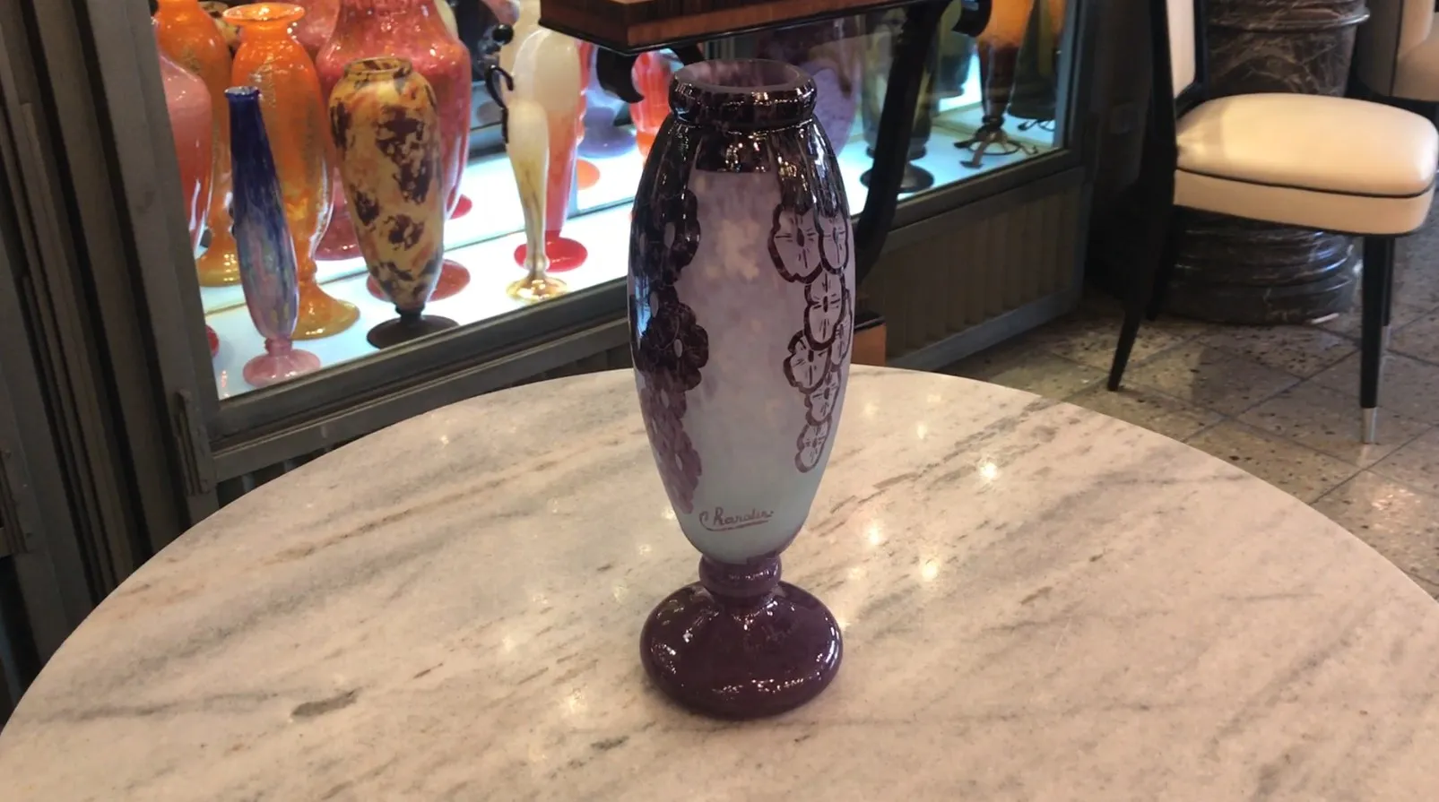 Vidrio firmado Charder con decoraciones en tonos morados, con fondo claro y relieve de flores.