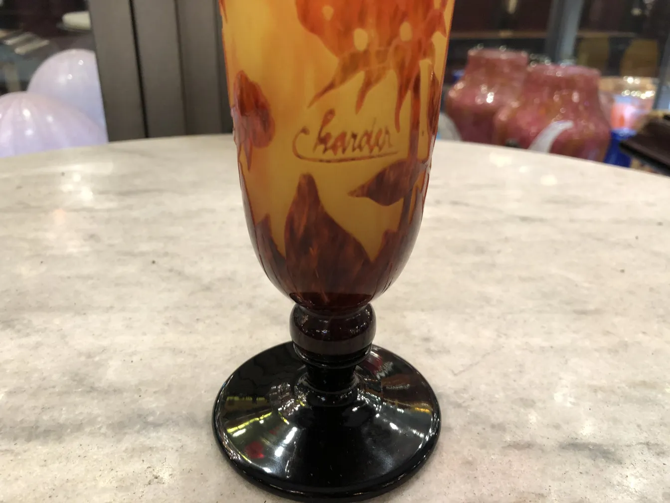 Vidro antigo assinado Charder com cores quentes, fundo claro.