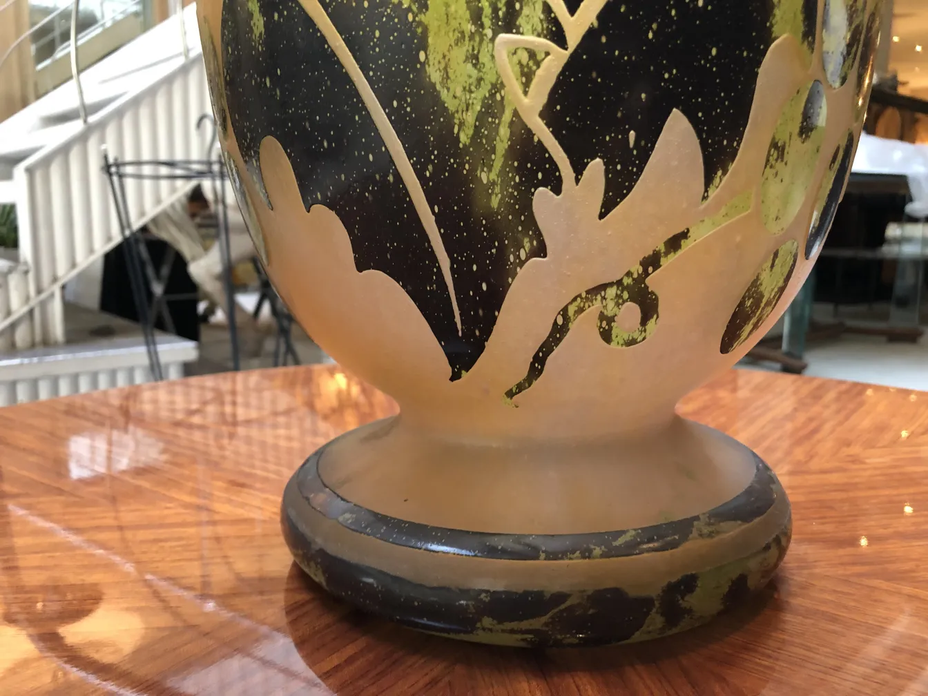 Vidro antigo assinado Degué com detalhes decorativos em tons escuros e verdes, sobre uma superfície de madeira.