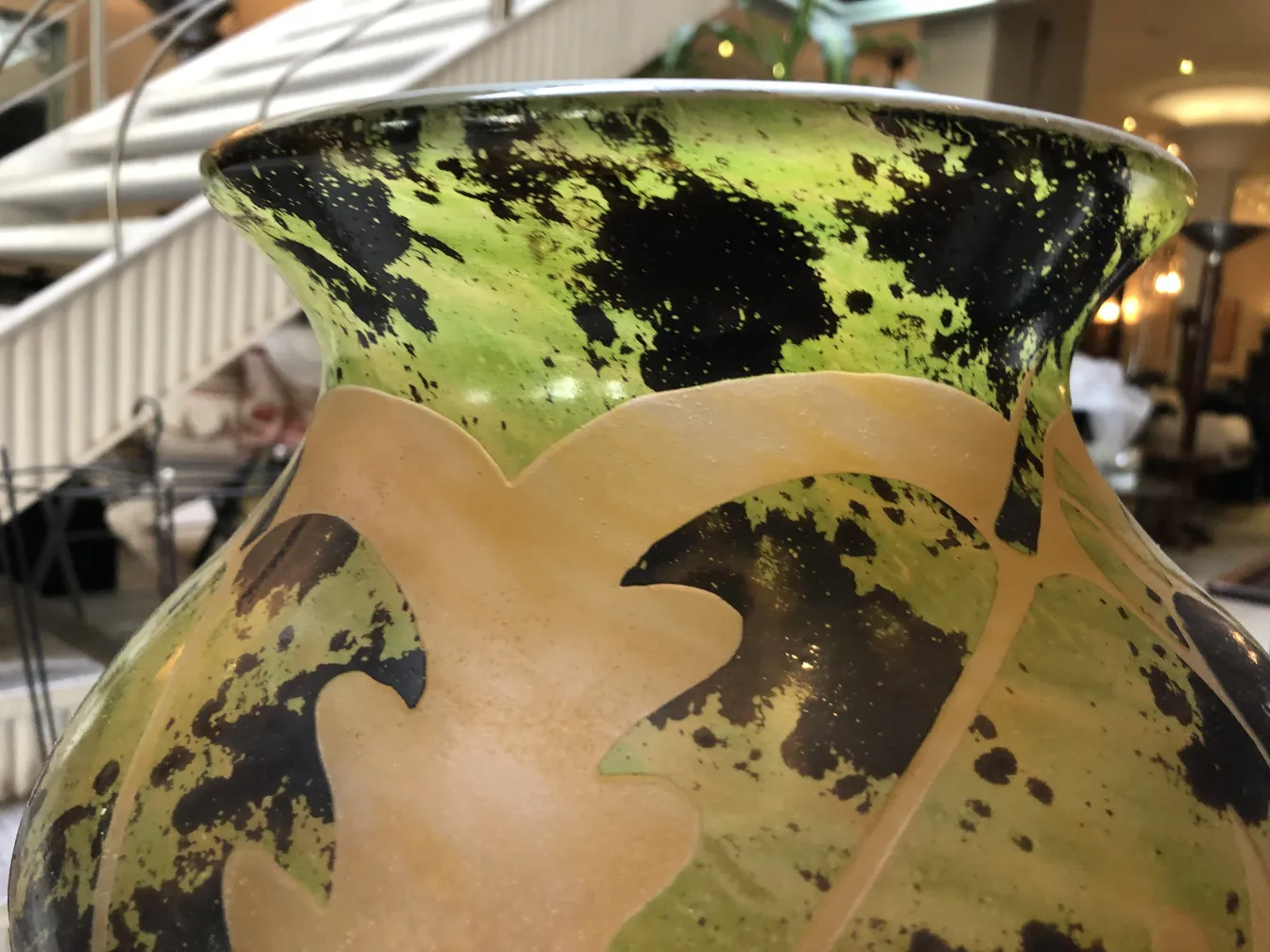 Vue latérale d'un verre antique signé Degué, aux couleurs vertes et noires.