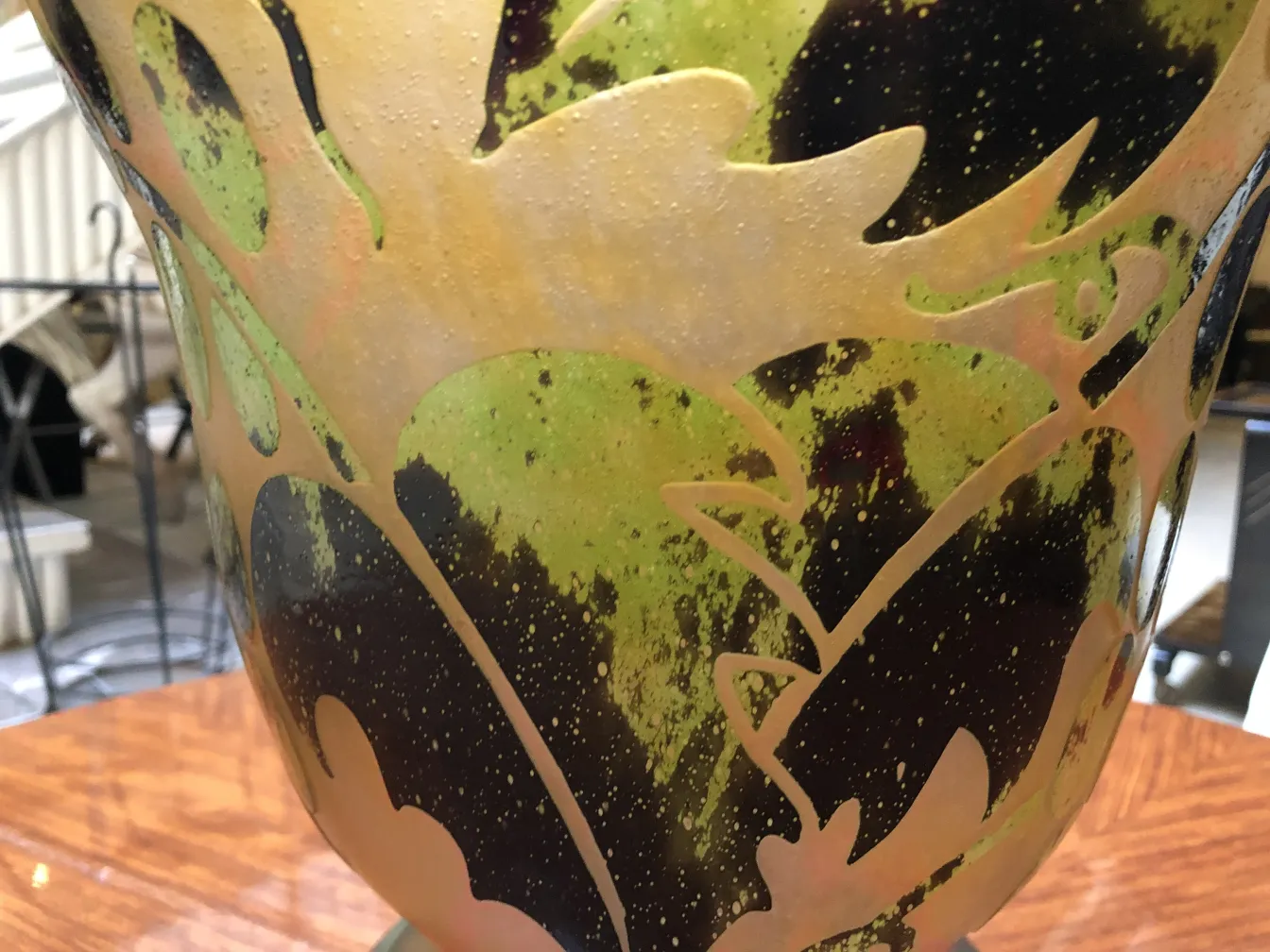 Signed Degué glass with intricate design in green and dark tones, set in an antique environment.