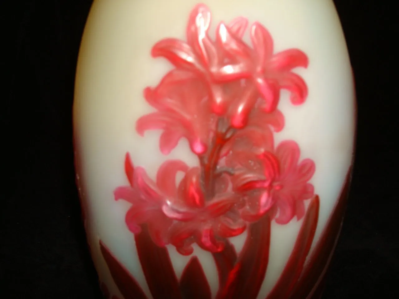 SIGNED GLASS Gallé featuring a floral design in red hues on a light background.