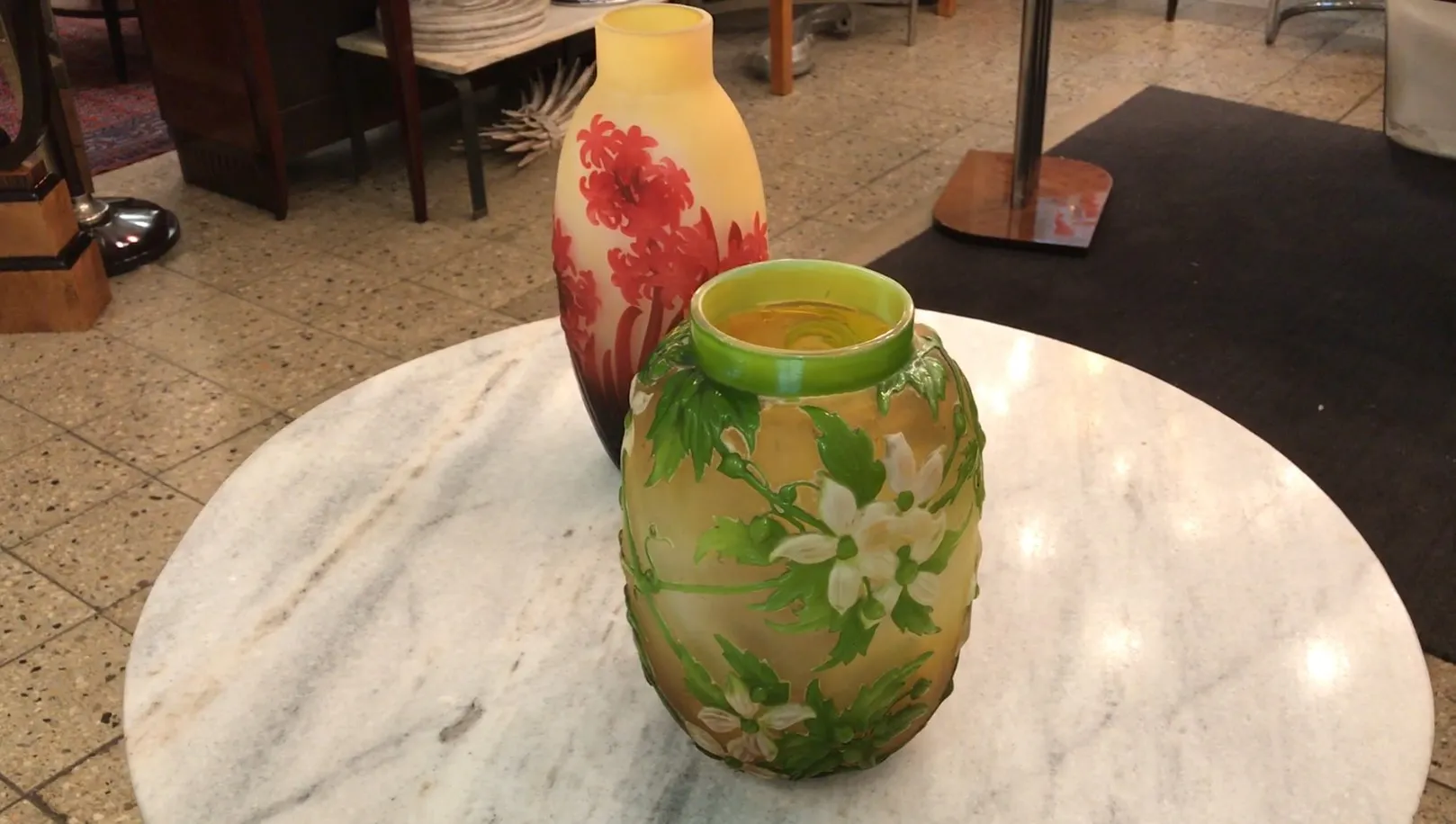 Deux vases antiques en verre signé Gallé avec des motifs floraux sur une table en marbre.