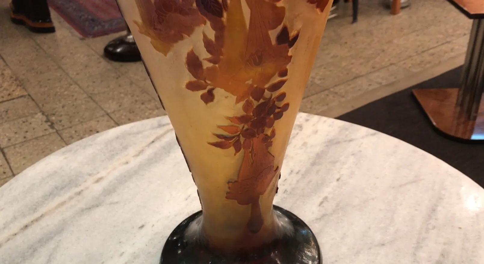 Antike Gallé Vase mit floralem Design auf einem farbverlauf Hintergrund, verziert mit bernsteinfarbigen und braunen Blättern.
