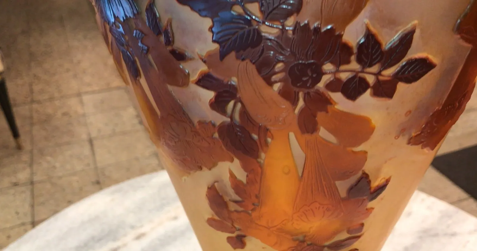 Verre ancien signé Gallé avec motif floral en relief, exposé dans un cadre élégant.