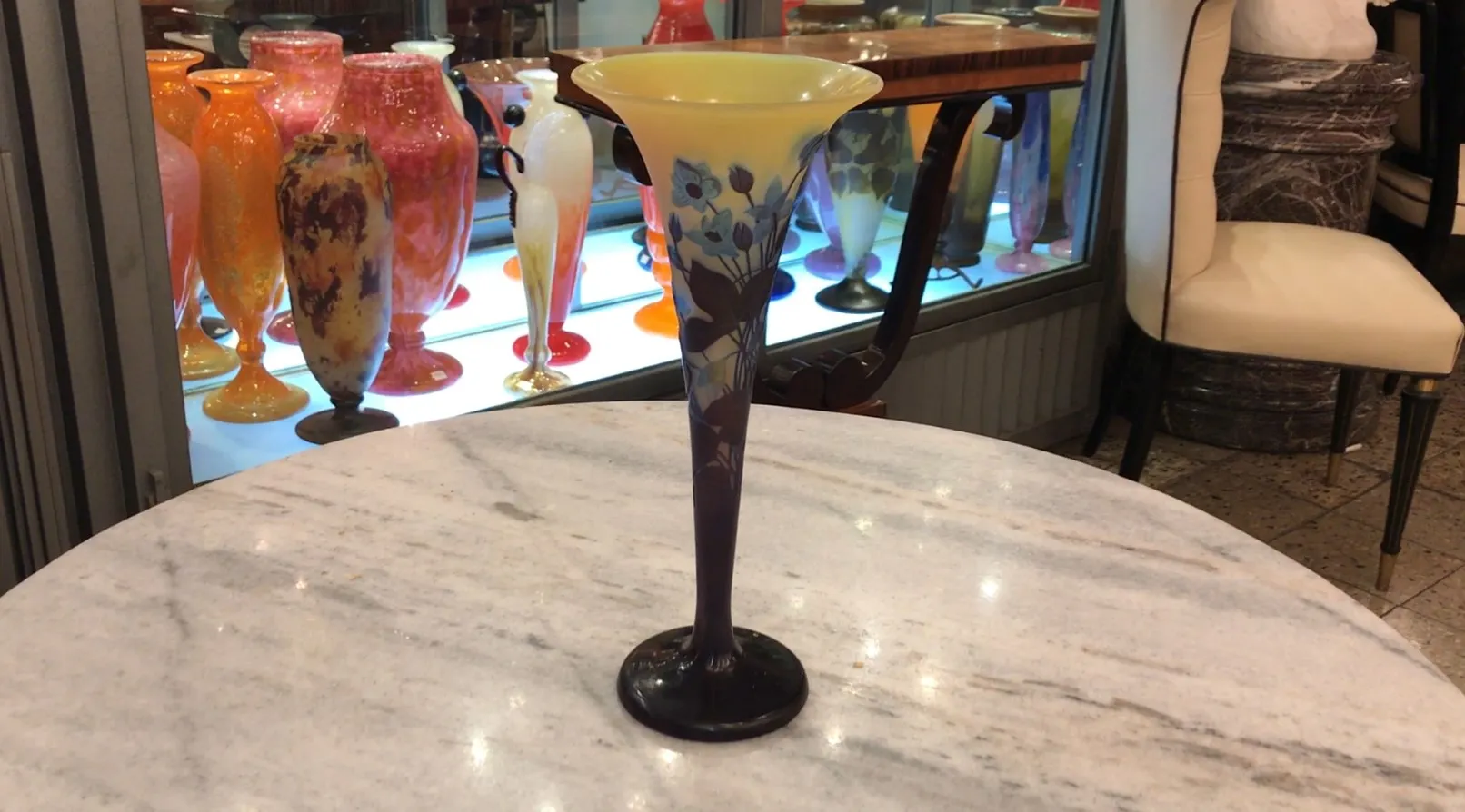 Elegante vidrio firmado Gallé con motivos florales, exhibido en un entorno de antigüedades.