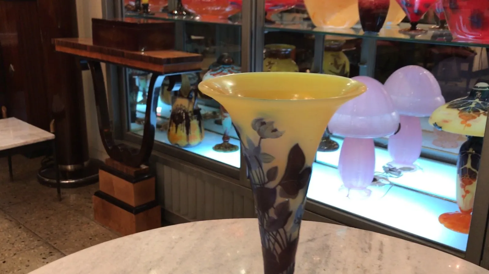 Signiertes Glas Gallé mit gelber und lila Dekoration in einem antiken Ambiente.