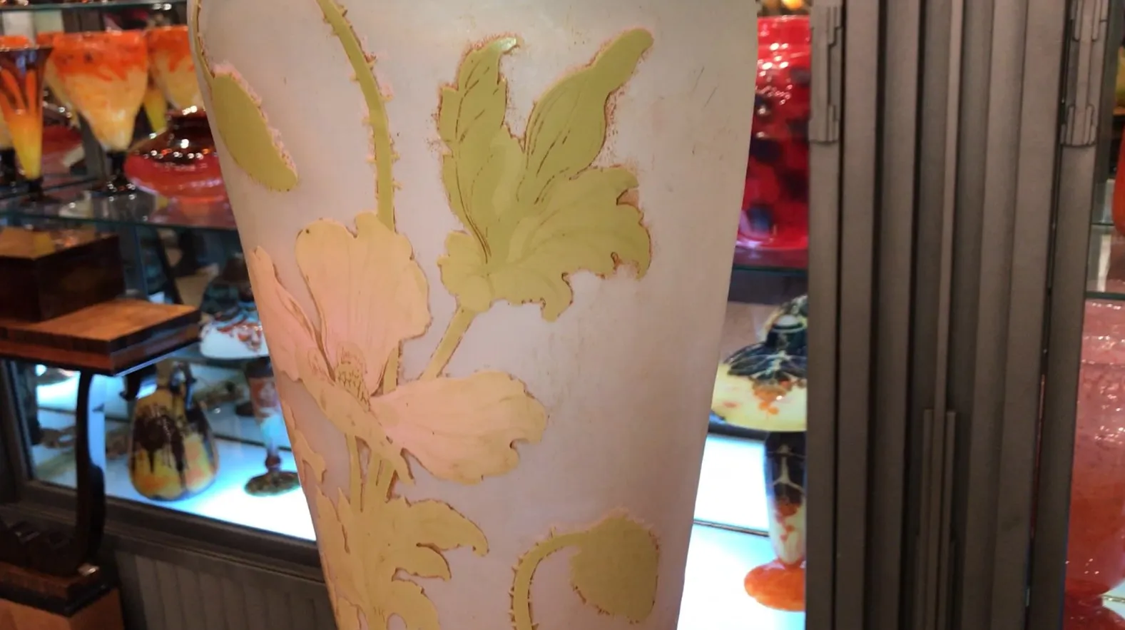 Vase ancien en verre signé Gallé avec un motif floral aux couleurs douces et fond clair.