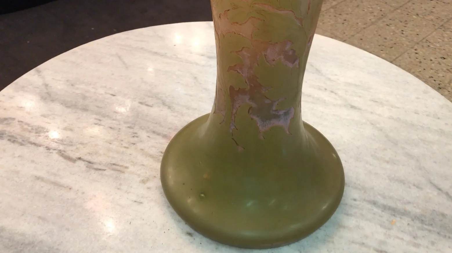 Verre signé Gallé avec un design décoratif en tons de vert et des détails subtils à la surface, sur une table.