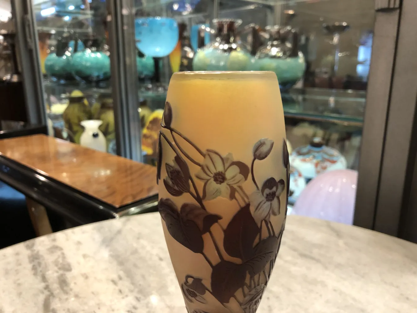 Vidro assinado Gallé com design floral e cor quente, em um ambiente vintage.