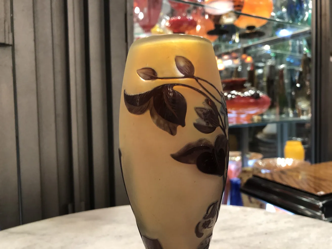 Vaso in vetro firmato Gallé in tonalità dorate e marroni, con decorazione di foglie, in un ambiente d'antiquariato.