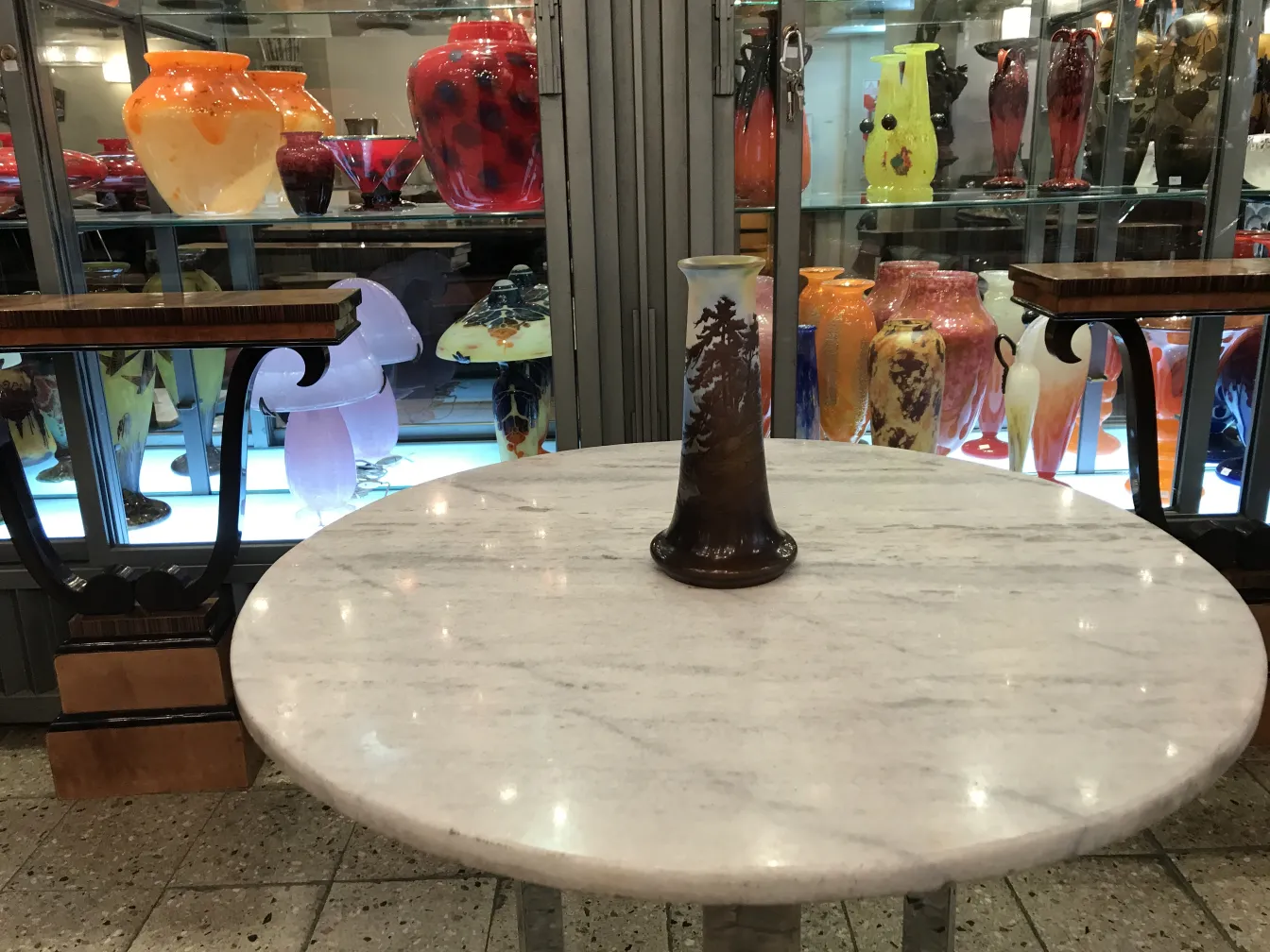 Antique signed glass Gallé on a table with colorful vases in the background