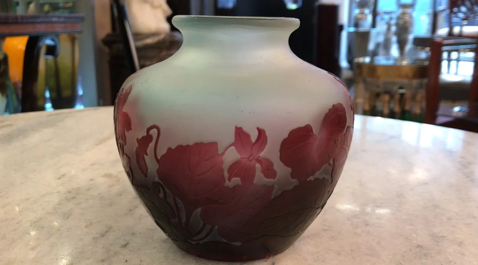 Antique signed glass Gallé with floral decoration in red and green tones, on a marble table.