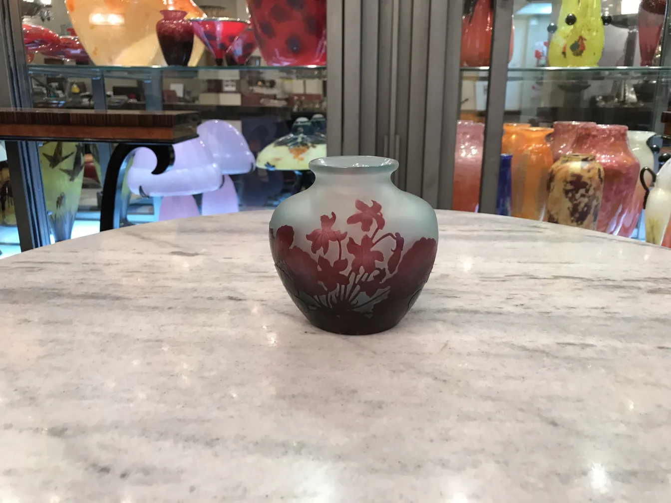 vaso pequeno de vidro assinado Gallé sobre mesa, fundo colorido