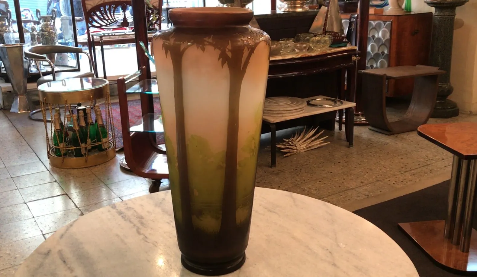 Vaso alto com desenho de palmeiras em um ambiente antigo.