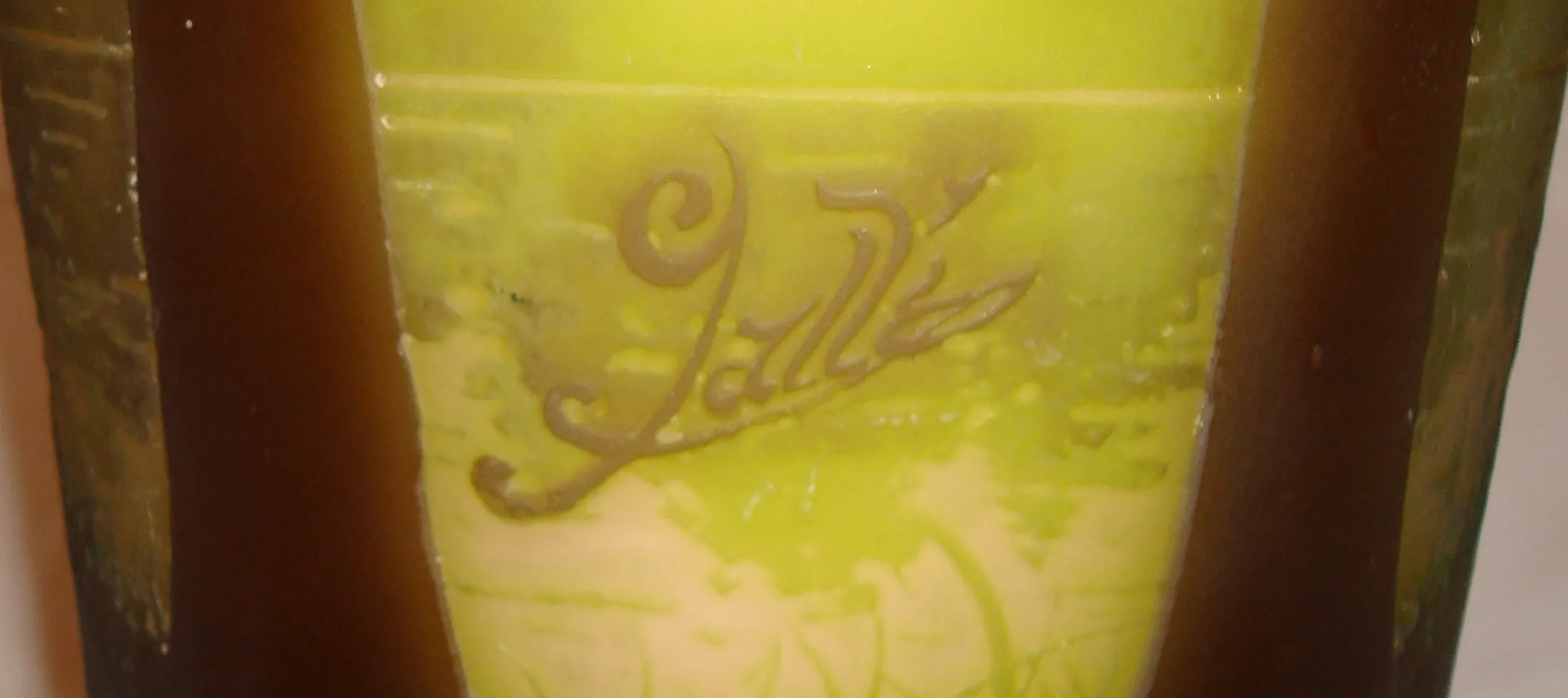 Signed Gallé glass with decorative green and yellow details, an antique in an elegant setting.